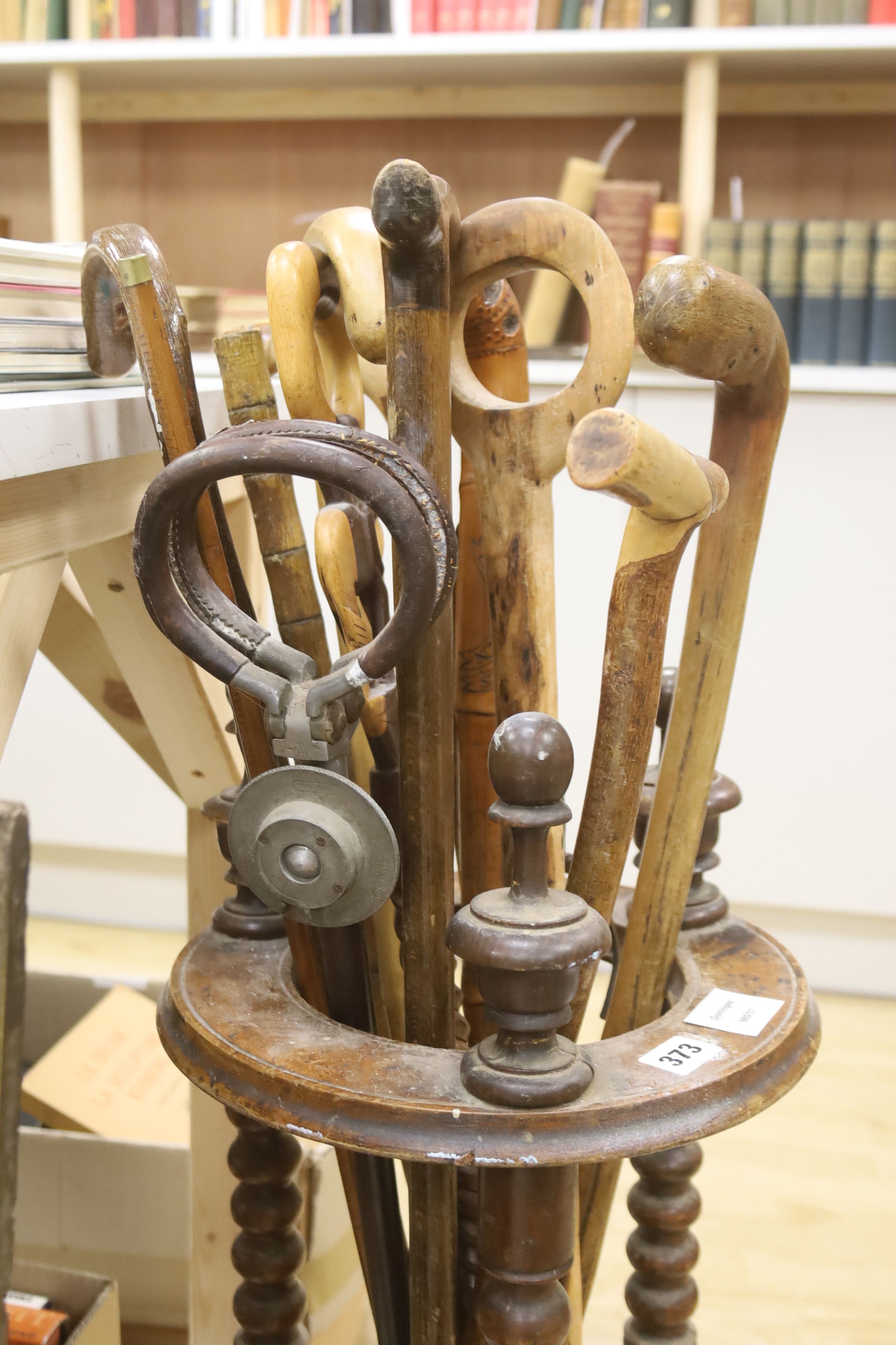 A circular turned beech stick stand, containing various walking sticks and a shooting stick